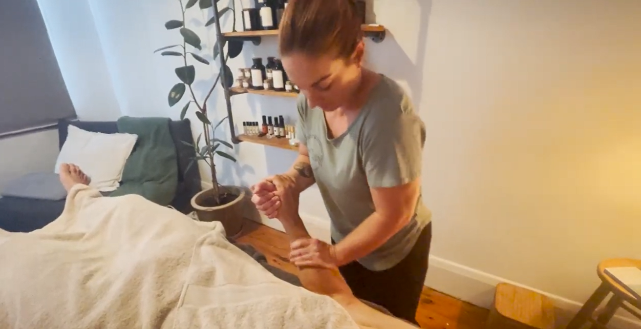 A massage therapist working on a client's arm in her treatment room