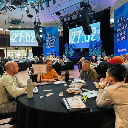 Jodie Coall working through business plans with owners around a table at a business event