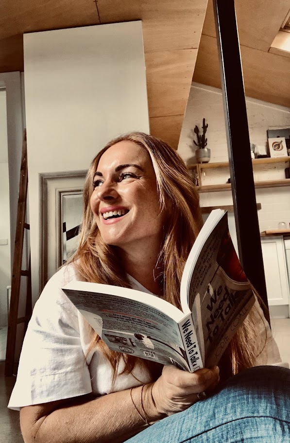 Jodie Coall, founder of WellBusi, laughing while holding a copy of her book